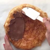 Steg 3 Nutellapizza: Bre ut nötkräm över smördegen med en slickepott.