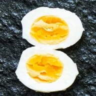 Kokt ägg med hårdkokt gula, delad i halvor mot svart botten.