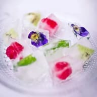 Isbitar med ingjutna blommor och frukter ligger på en glasskål.