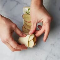 Smördeg med färskost och potatisskivor rullas försiktigt ihop.