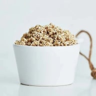 En skål fylld med quinoa står på en vit yta.