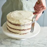 Pannacottan breds runt tårtan och jämnas till med hjälp av en palett