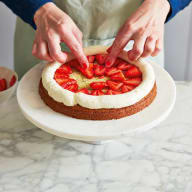 Flädermarinerade jordgubbar placeras i mitten av tårtbotten, innanför den spritsade panncottan.