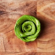 En avokado skuren i en spiralform ligger på en träskärbräda.