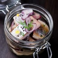 En glasburk innehåller fiskbitar, lökringar och örter.