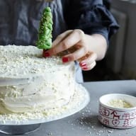 Hand sätter ner marsipangran i en vit tårta