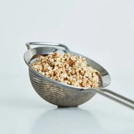 En metallsil innehåller krossade nötter eller frön.