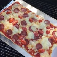 En nygräddad pizza som bakats på en grill.