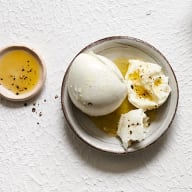 En tallrik med mozzarella och en skål med olivolja står på en vit yta.