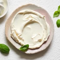 En tallrik med krämig sås garnerad med basilikablad.