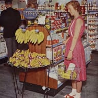 En kvinna står vid en hylla med bananer - en bild tagen från en ICA-butik 1961.
