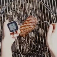 En köttbit som grillas på en grill, en digital termometer sitter instucken på en sidan och visar köttets innertemperatur på 41 grader.
