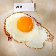 Ett stekt ägg ligger på ett papper bredvid en lapp med texten 