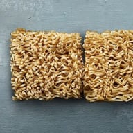 Tre rektangulära block av torkade nudlar ligger på en slät yta.