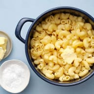 En kastrull med pasta och två mindre skålar med smör och mjöl står på en yta.
