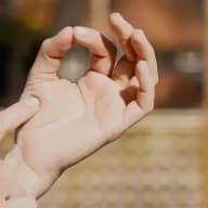 En hand där tumme och pekfinger möts samt ett pekfinger som petar på handflatan.