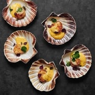 Fem musslor med mat serveras på en mörk yta.