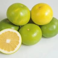 Flera citrusfrukter ligger samlade, varav en är delad på mitten och visar fruktköttet.