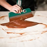 Smält choklad som skrapas på en marmorskiva