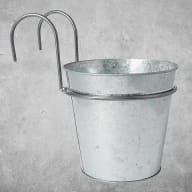 En metallhink med handtag hänger på en krok.