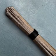 En bunt smala träpinnar hålls samman av ett mörkt band mot en grå bakgrund.