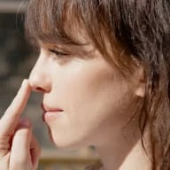 En kvinna i profil som tar sig på nästippen med pekfingret.