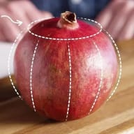 En pomegranate med streckade linjer ritade på skalet ligger på en träyta.