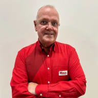 En person med glasögon bär en skjorta med ett Maxi-märke och har armarna i kors.