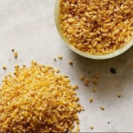 En skål med bulgur och en hög med bulgur på en yta.
