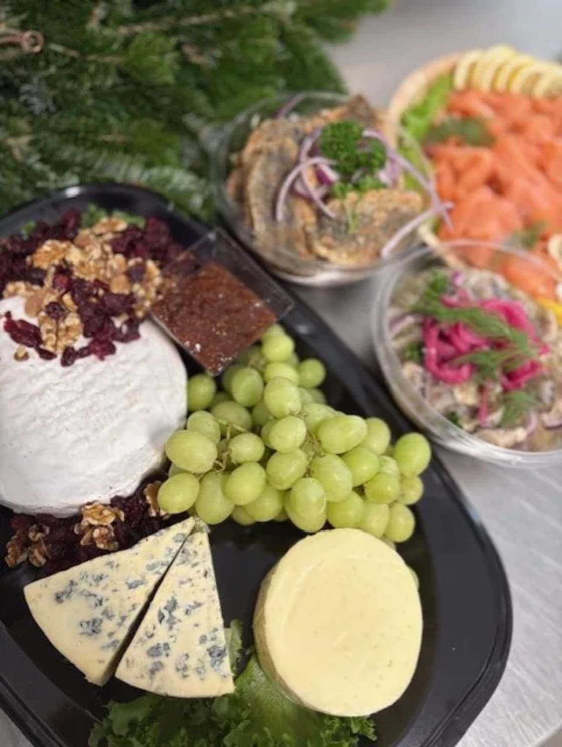 Ostbricka med flera ostar, en klase vindruvor och olika tillbehör.