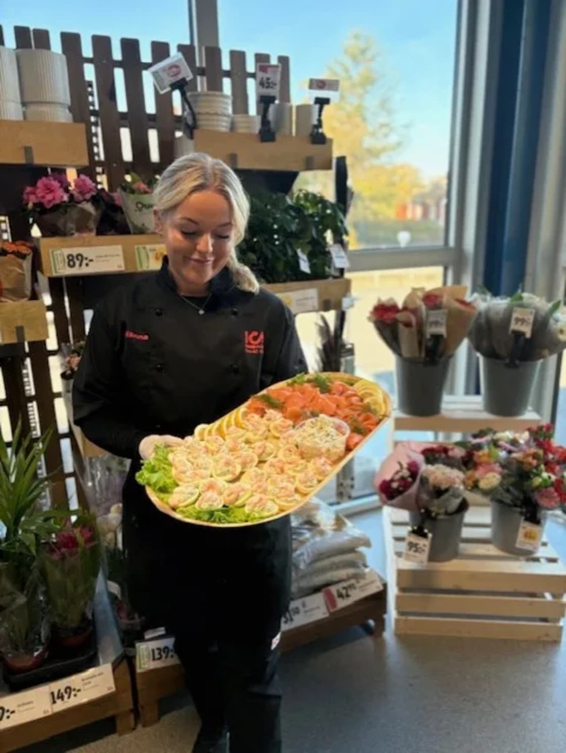 En person i butik håller ett stort serveringsfat med upplagda snittar.