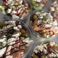 Flera portionssallader med ost, oliver, skivad lax och dressing.