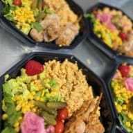 Flera plastskålar fyllda med sallad, pasta, olika grönsaker och tillagad kyckling.
