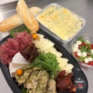 Plocktallrik med charkuterier, ostar, bröd och flera tillbehör.