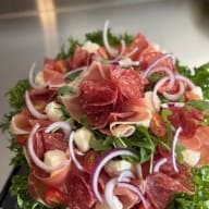 Upplagd sallad med skivad salami och prosciutto, mozzarella, körsbärstomater och skivad lök.