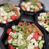 Närbild av flera salladsportioner med vattenmelon, fetaost, gurka och färska örter.