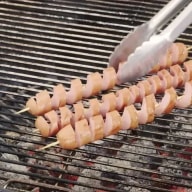 Tre spiralkorvar grillas på en kolgrill.