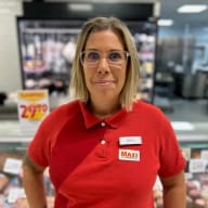 En person med glasögon står framför en kyldisk i en butik.