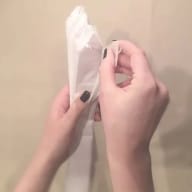 En person håller i en bit papper och fäster det på en vägg.