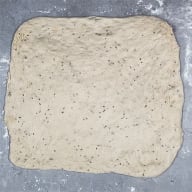 En deg med små mörka prickar ligger utbredd på en yta.