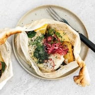 En tallrik med en öppen wrap fylld med grönsaker och kryddor, bredvid en gaffel.
