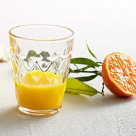 ett glas med citrusshot och en uppskuren apelsin ligger bredvid