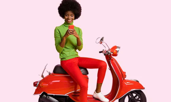 En person sitter på en moped och håller en mobiltelefon.