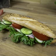 En smörgås med grönsaker ligger på ett träbord.