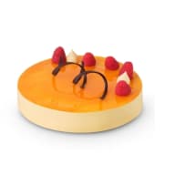 Moussetårta med mangosmak elegant dekorerad med färska hallon och choklad.