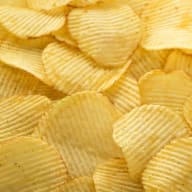 Potatischips med räfflad yta ligger i en hög.