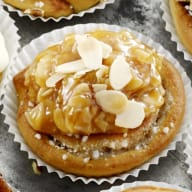 En tallrik med olika små bakverk och cupcakes står på ett bord tillsammans med skålar fyllda med godis och frukt.