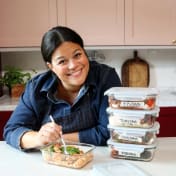 ICA:s vardagskock sitter vid ett bord med en gaffel i en matlåda och flera staplade matlådor.