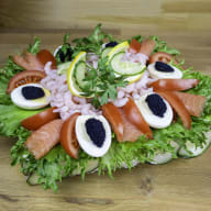 En tallrik med sallad, lax, ägg och kaviar ligger på ett bord.