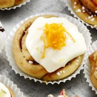 En tallrik med olika små bakverk och cupcakes står på ett bord tillsammans med skålar fyllda med godis och frukt.